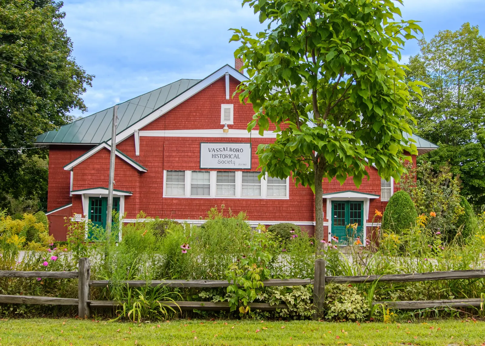 The Vassalboro Historical Society building in summer, with the front gardens in bloom