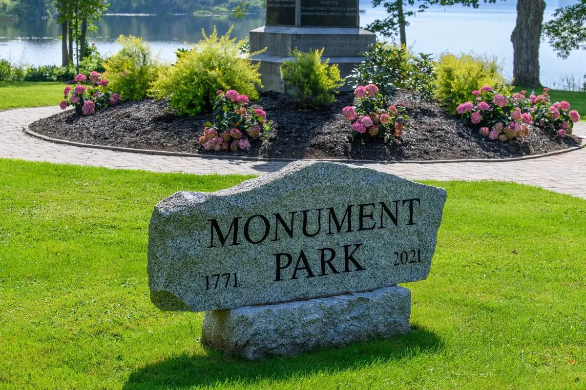 Monument Park sign, Vassalboro, with the war memorial and gardens behind it
