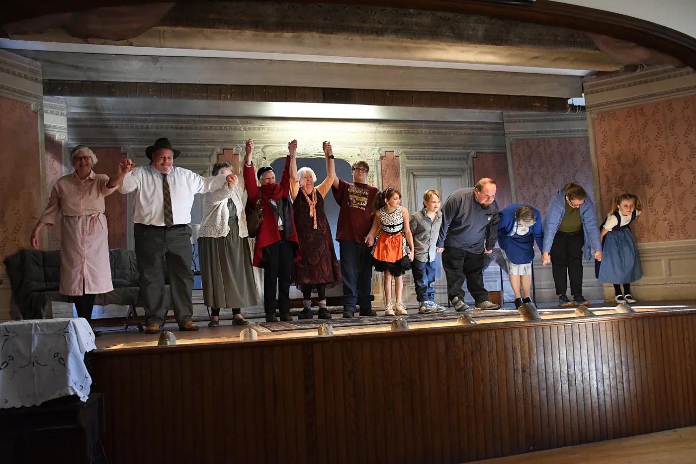 Full company on stage at the curtain call with hands joined and raised