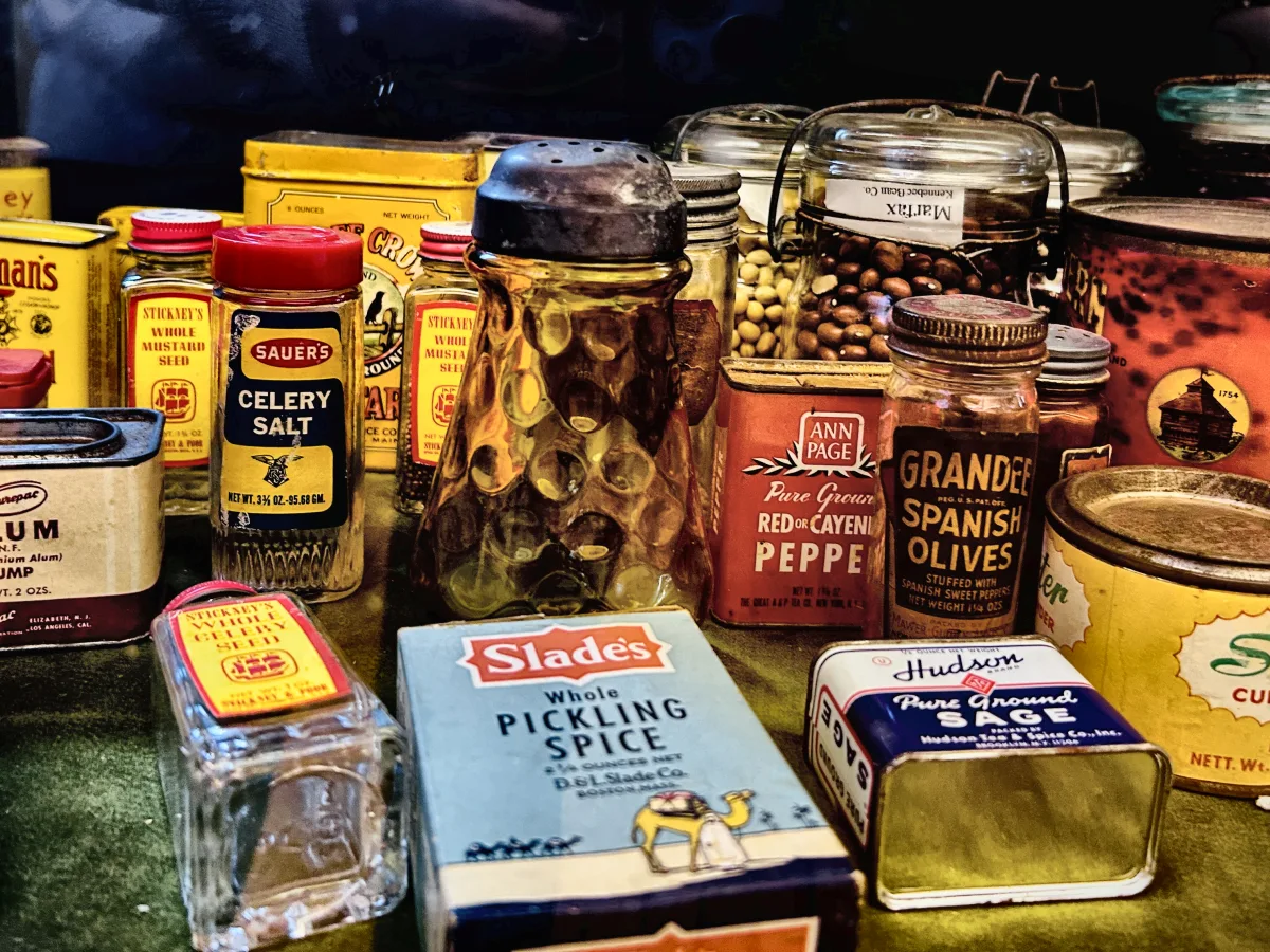 Crowded shelf of vintage spice tins, jars and boxes