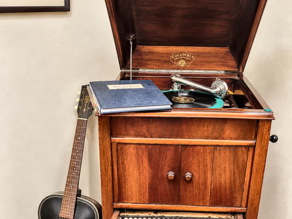 Columbia Grafonola phonograph cabinet with a guitar leaning against it