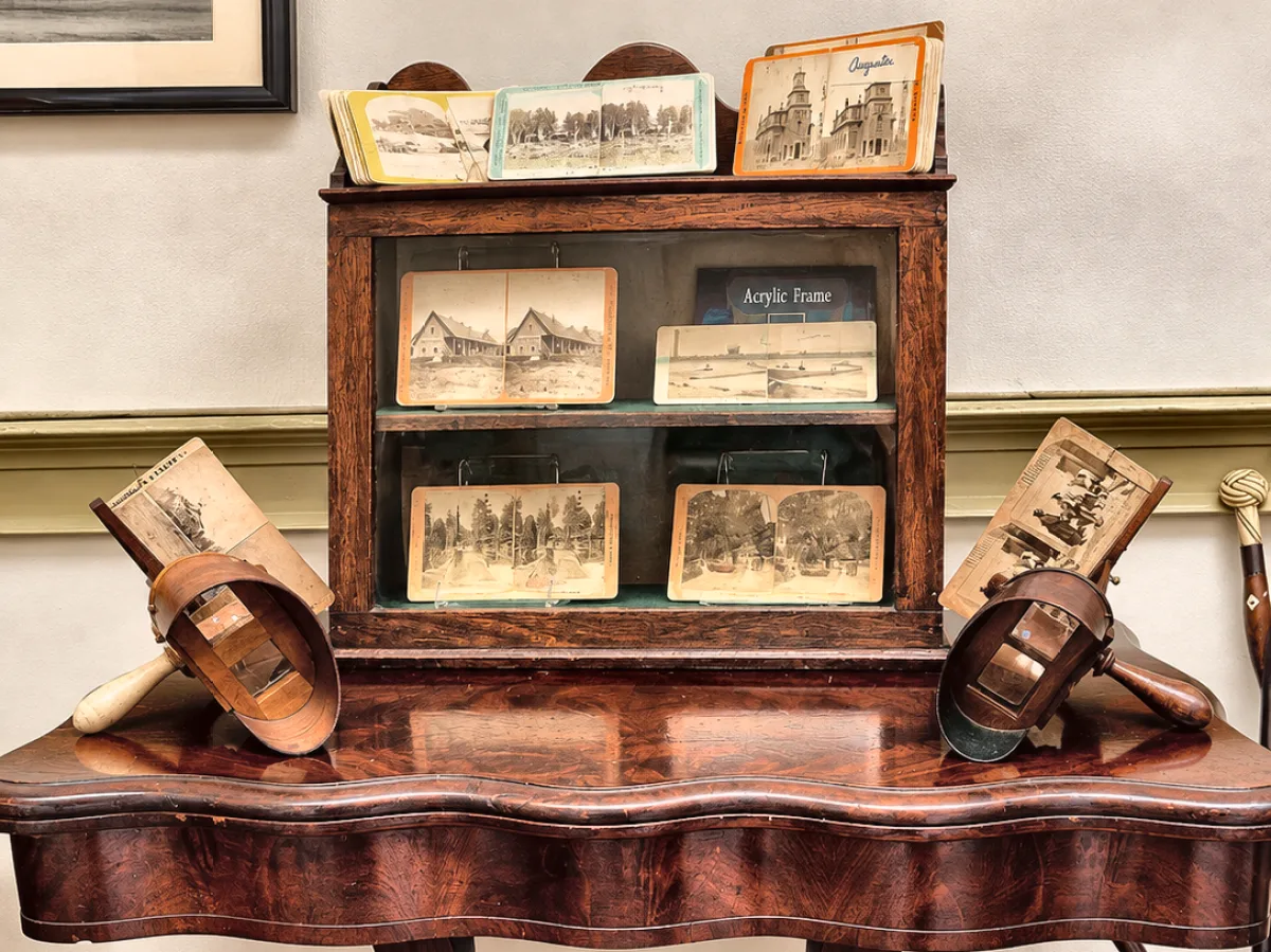 Card table holding a stereoscope cabinet, two viewers and rows of stereo view cards