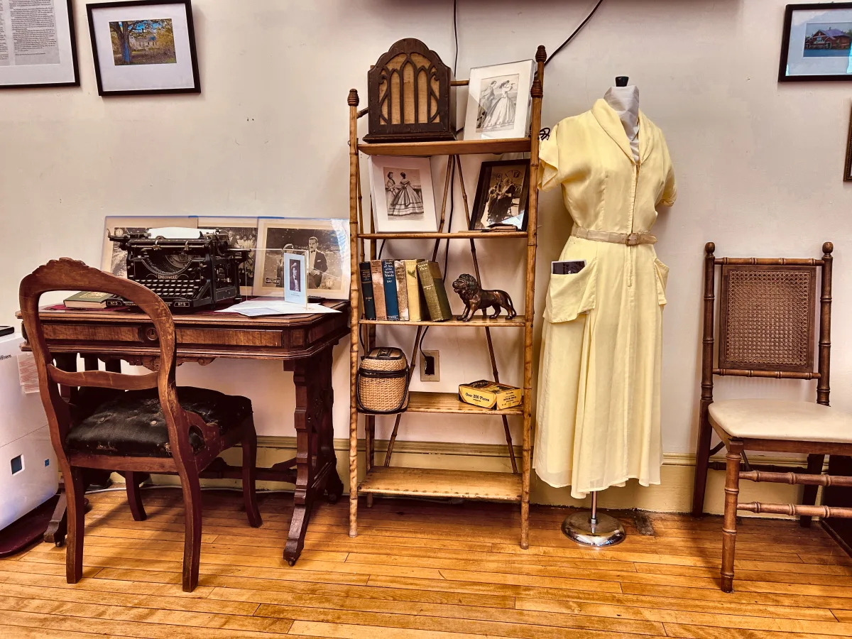 Underwood No. 5 typewriter on a parlor table beside a bamboo shelf and a pale yellow dress