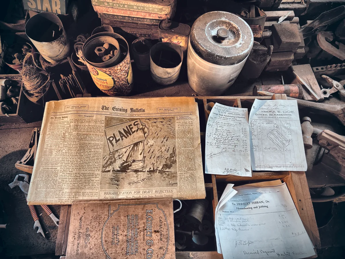 Handwritten blacksmith bills and a 1942 newspaper spread on a workbench