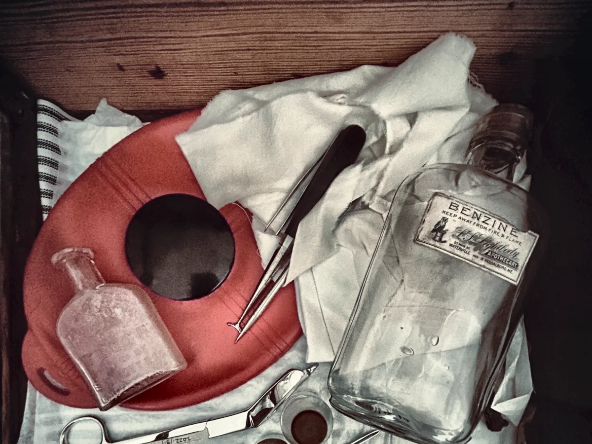 Surgical instruments, a glass benzine bottle and folded cloths in a tray