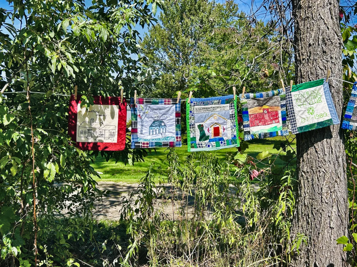 Quilt blocks showing the Ballard House, the Getchell&rsquo;s Corner chapel and a Riverside All Stars 4-H block