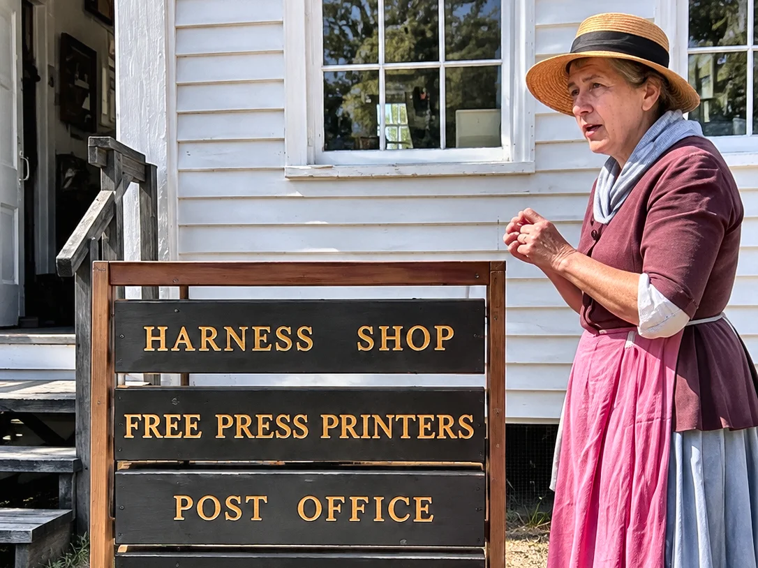 The Heritage Village sign board standing outside the white clapboard shop building