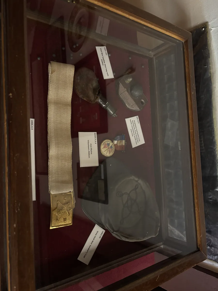 Civil War case with a leather shot bag and pellets, grapeshot from Gettysburg mounted on wood, 21st Maine Volunteers ribbon, and a grey Civil War soldier's cap